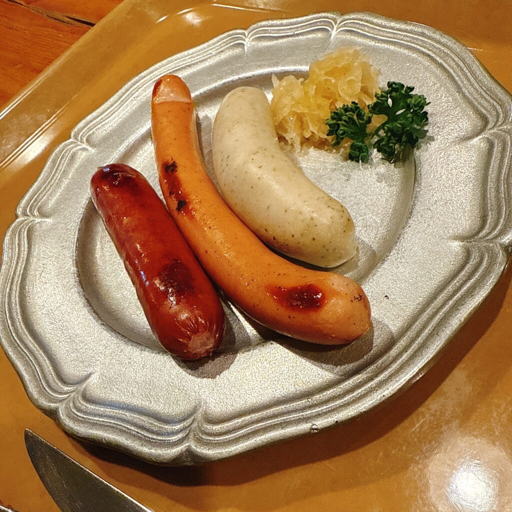 焼き目の付いた3種類のソーセージとザワークラウトの盛り合わせ