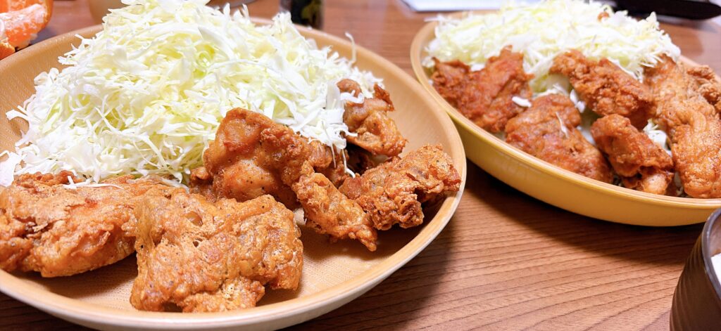 唐揚げと千切りキャベツを二つの皿に盛り付けた食卓